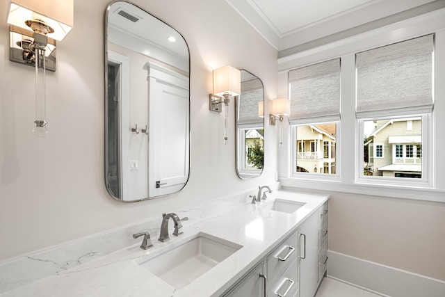 bathroom featuring crown molding, double vanity, baseboards, and a sink