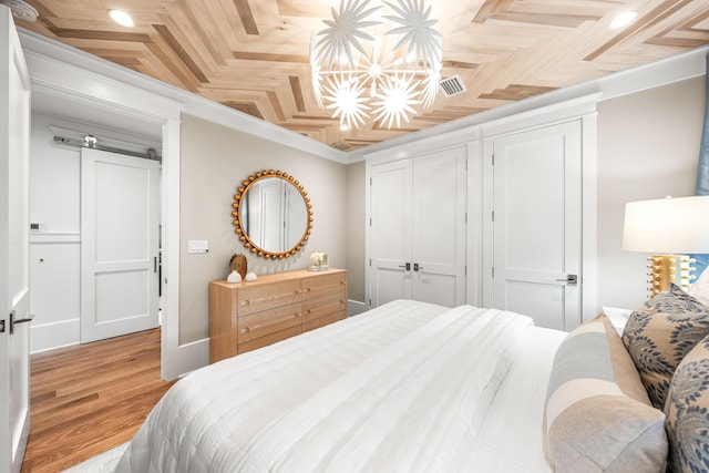 bedroom featuring crown molding, visible vents, light wood-type flooring, and a closet