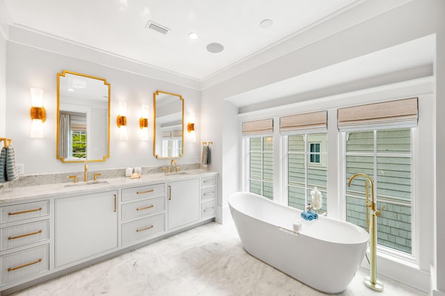 full bathroom featuring visible vents, double vanity, a freestanding tub, a sink, and marble finish floor