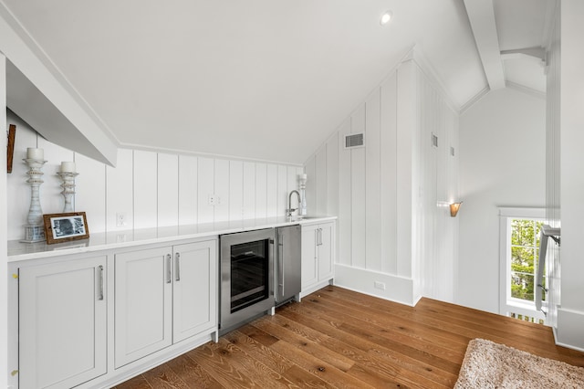 bar featuring visible vents, wine cooler, lofted ceiling, dark wood-style flooring, and a sink