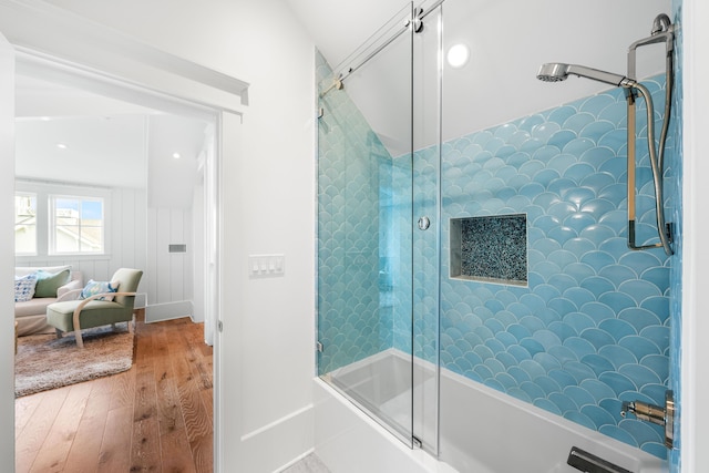 full bath with wood finished floors and bath / shower combo with glass door