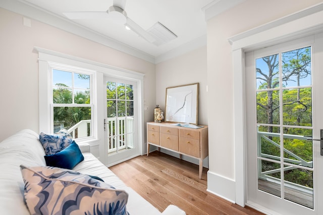 doorway to outside featuring light wood-type flooring, visible vents, ceiling fan, and crown molding