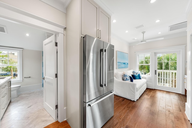 kitchen with light wood-style floors, plenty of natural light, high quality fridge, and ornamental molding