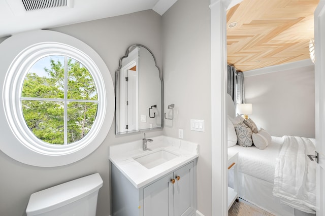 bathroom with visible vents, toilet, vanity, and lofted ceiling