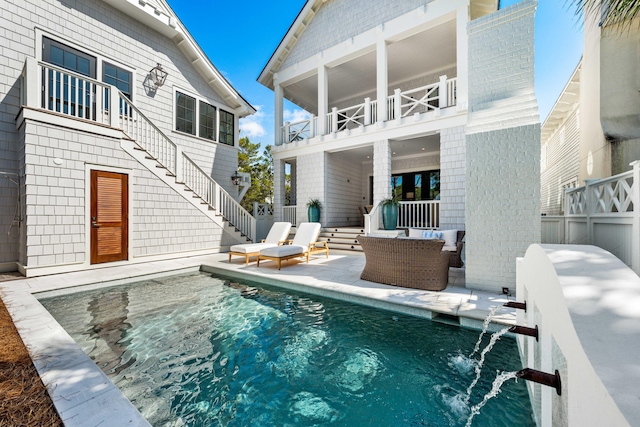 rear view of house with fence, stairs, a balcony, a patio area, and an outdoor pool