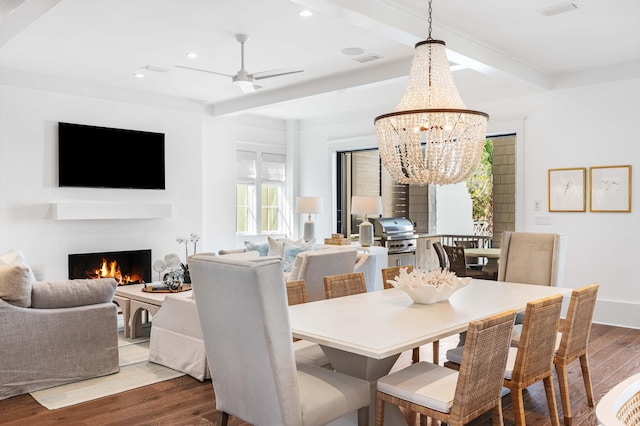 dining room with beamed ceiling, wood finished floors, visible vents, and a lit fireplace