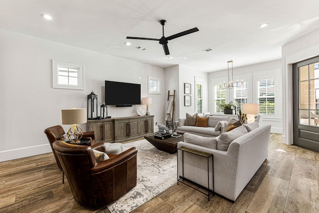 living room featuring hardwood / wood-style floors and ceiling fan with notable chandelier