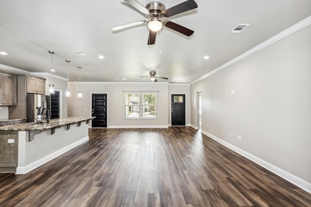 kitchen with a breakfast bar, light stone countertops, dark hardwood / wood-style floors, stainless steel refrigerator with ice dispenser, and decorative light fixtures