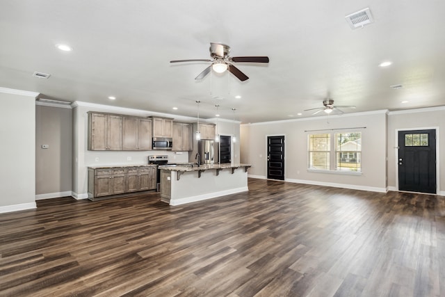 kitchen featuring a center island with sink, stainless steel appliances, ornamental molding, a breakfast bar area, and dark hardwood / wood-style floors