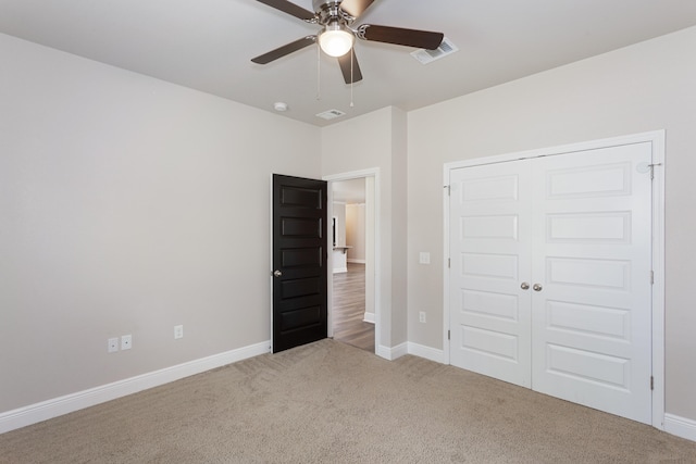 unfurnished bedroom featuring a closet, ceiling fan, and light colored carpet