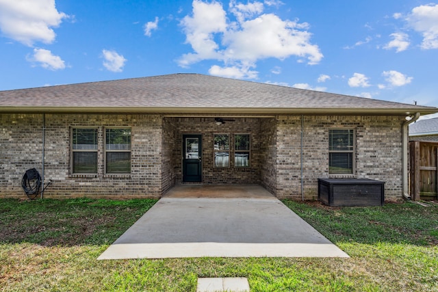 view of exterior entry with a patio, ceiling fan, and a lawn