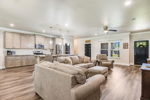 living room with hardwood / wood-style floors, crown molding, and ceiling fan