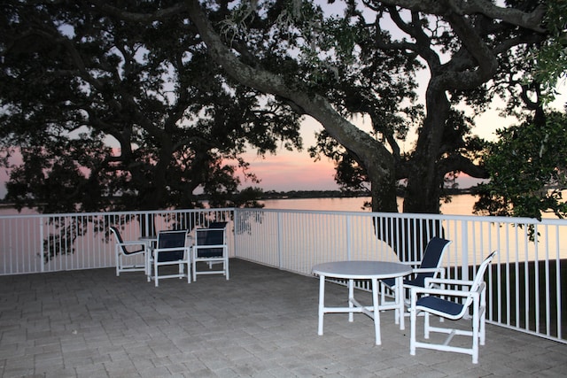 patio terrace at dusk featuring a water view