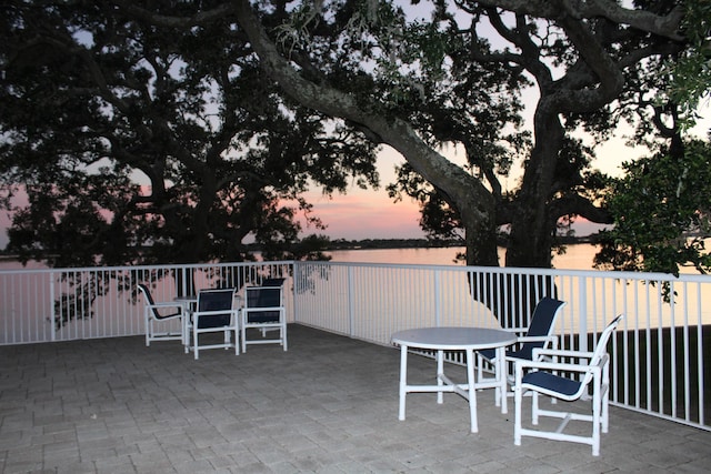 209 W Miracle Strip Pkwy Apt A104, Mary Esther, FL 32569 - patio terrace at dusk with outdoor dining space and a water view