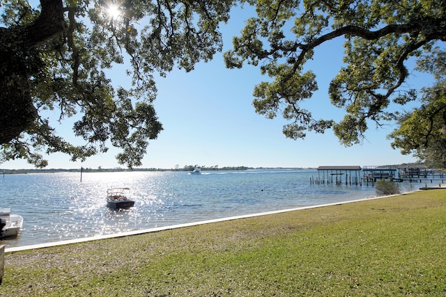 view of dock with a yard and a water view