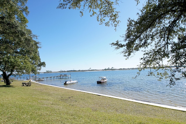 view of dock with a water view and a yard