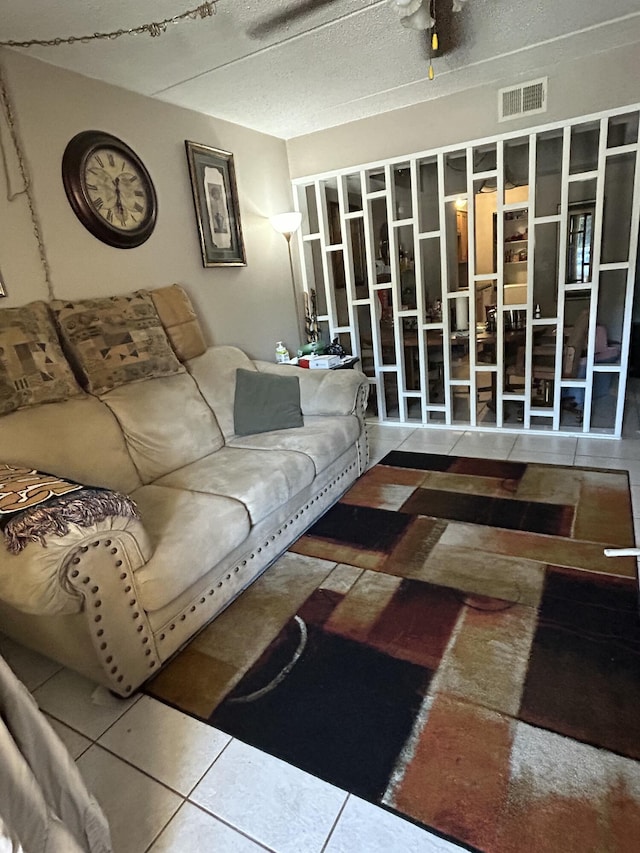 living room with tile patterned flooring, a textured ceiling, and ceiling fan