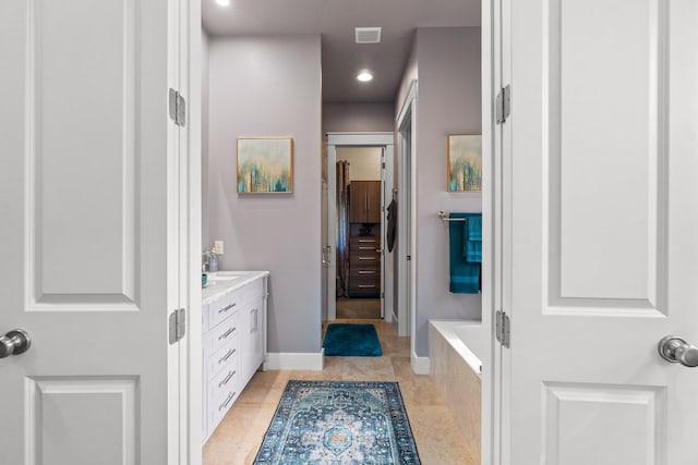 bathroom with vanity, tile patterned flooring, and tiled bath