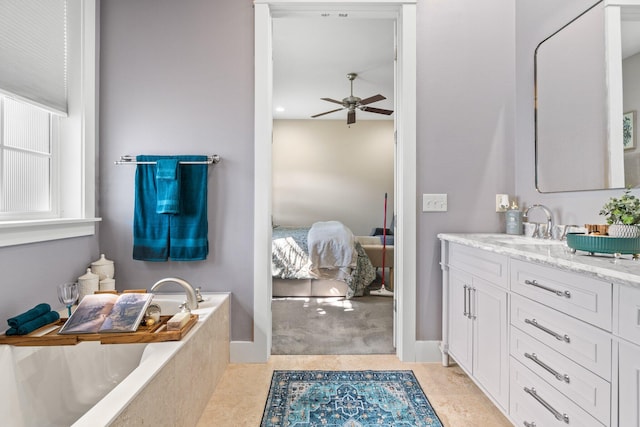 bathroom with vanity, tiled tub, and ceiling fan