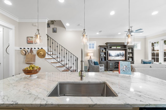 kitchen featuring ornamental molding, light stone counters, pendant lighting, and ceiling fan