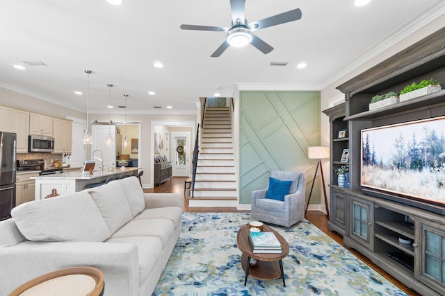 living room featuring ceiling fan, hardwood / wood-style flooring, ornamental molding, and sink