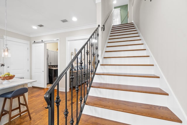 stairs featuring crown molding, a barn door, and hardwood / wood-style floors