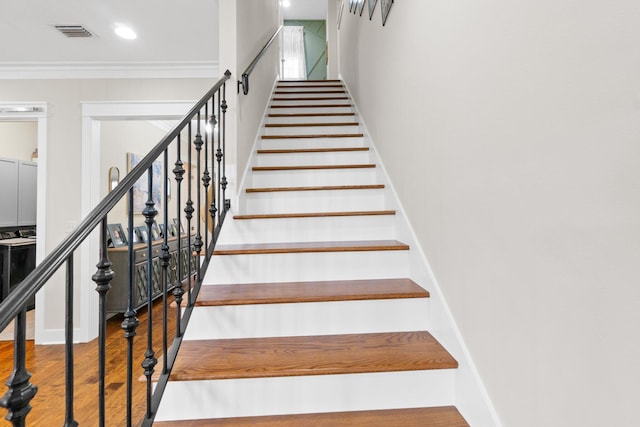 staircase featuring crown molding and hardwood / wood-style floors