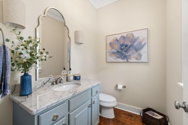 bathroom with vanity, toilet, crown molding, and hardwood / wood-style floors