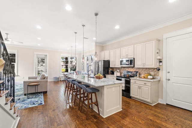 kitchen featuring an island with sink, a kitchen bar, dark hardwood / wood-style floors, pendant lighting, and stainless steel appliances