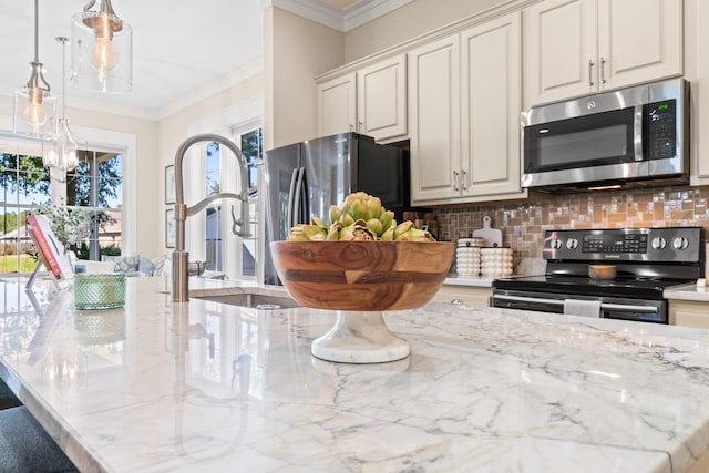 kitchen with backsplash, stainless steel appliances, decorative light fixtures, white cabinets, and ornamental molding