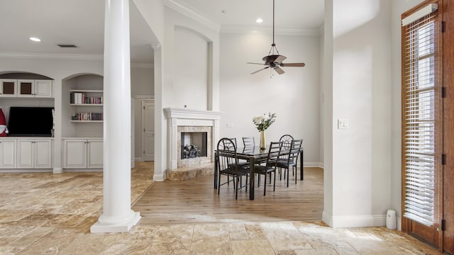 dining space with light hardwood / wood-style flooring, ceiling fan, built in features, ornamental molding, and a premium fireplace