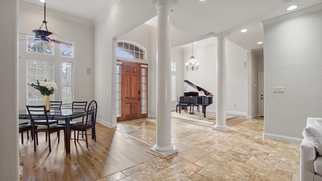 foyer with decorative columns, ornamental molding, ceiling fan with notable chandelier, light hardwood / wood-style flooring, and a high ceiling