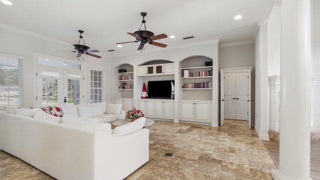 living room featuring french doors, decorative columns, built in shelves, ceiling fan, and crown molding