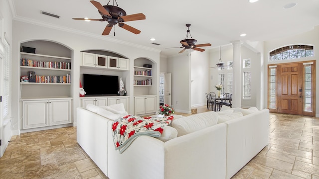 living room with ornate columns, ceiling fan, built in features, and ornamental molding