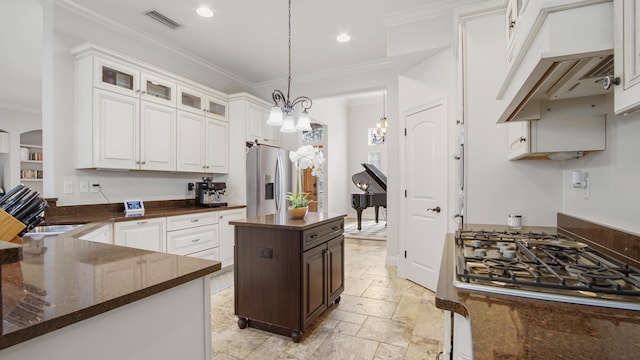 kitchen with white cabinets, appliances with stainless steel finishes, hanging light fixtures, and crown molding