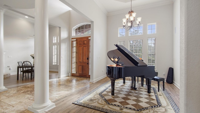 entrance foyer featuring decorative columns, crown molding, light hardwood / wood-style flooring, a chandelier, and a high ceiling