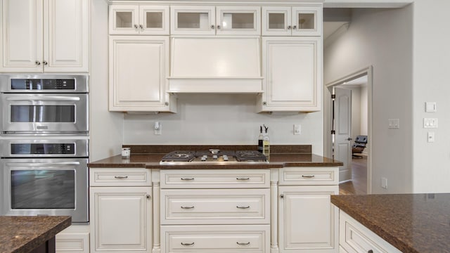 kitchen with white cabinets, dark stone countertops, custom range hood, and stainless steel appliances