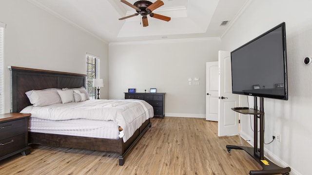 bedroom with a tray ceiling, light hardwood / wood-style flooring, ceiling fan, and crown molding