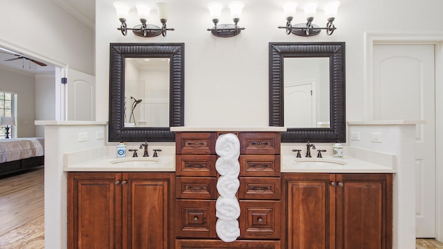 bathroom with hardwood / wood-style floors, ceiling fan with notable chandelier, ornamental molding, and vanity