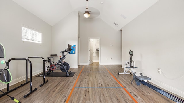 exercise room featuring hardwood / wood-style floors and high vaulted ceiling