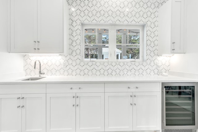 kitchen featuring white cabinetry, backsplash, sink, and beverage cooler