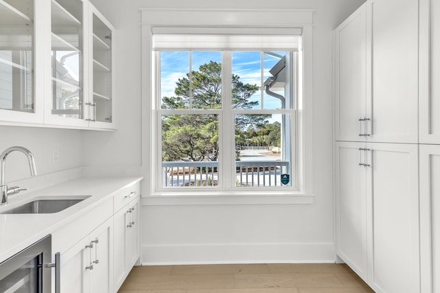 interior space featuring sink, light wood-type flooring, and beverage cooler