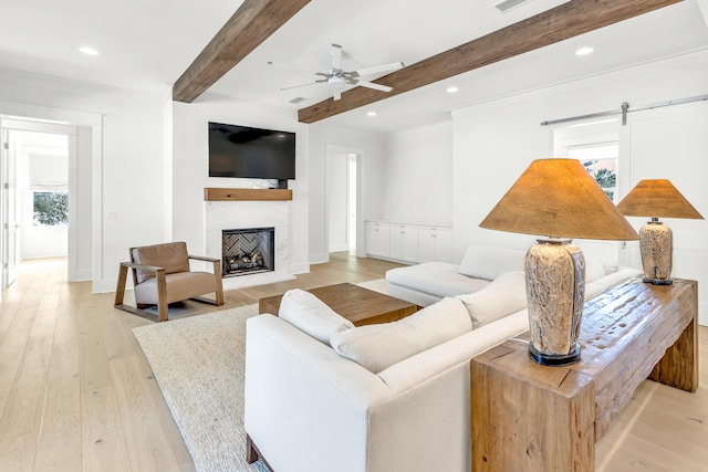 living room with ceiling fan, beamed ceiling, light wood-type flooring, and a barn door