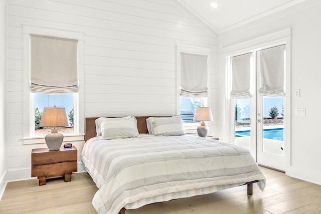 bedroom featuring lofted ceiling, ornamental molding, access to exterior, and light wood-type flooring