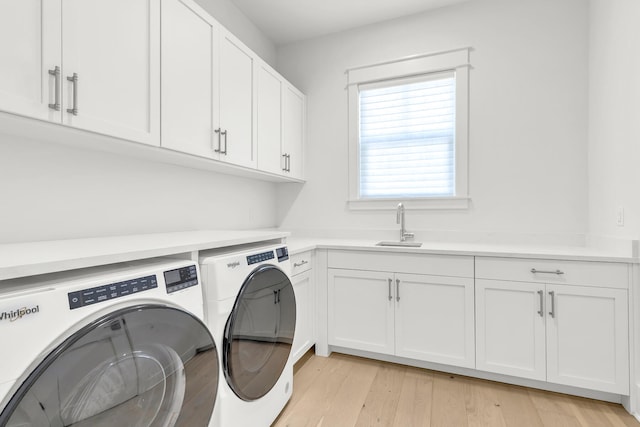 washroom with sink, independent washer and dryer, cabinets, and light hardwood / wood-style floors