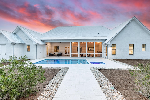 pool at dusk with a patio area and ceiling fan