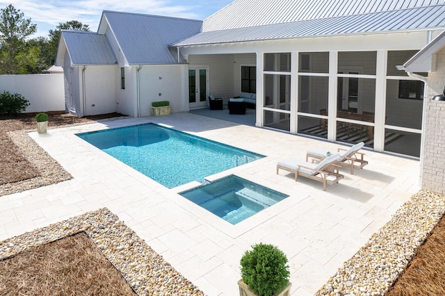 view of swimming pool with a patio, fence, a pool with connected hot tub, a sunroom, and french doors