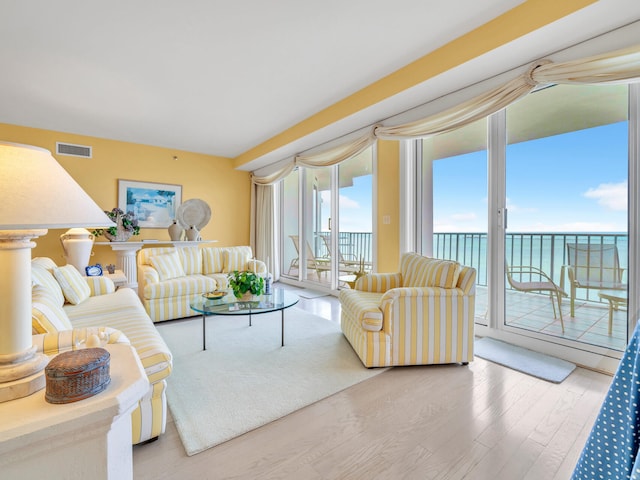 living area with plenty of natural light, wood finished floors, visible vents, and a water view