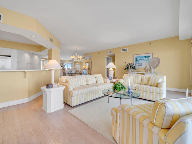 living area with light wood-style flooring, visible vents, and an inviting chandelier