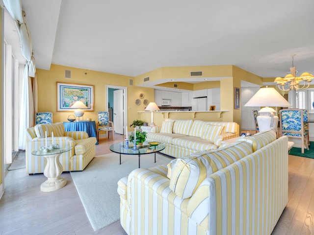 living room featuring light wood-style flooring, visible vents, and an inviting chandelier